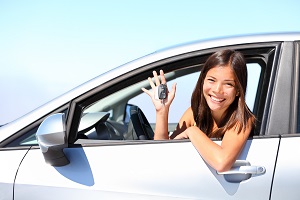 girl sitting in car holding up car keys smiling at camera